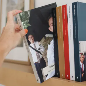 A hand pulling a missionary book from a shelf of finished books