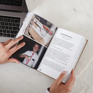 An open missionary book on a desk beside a laptop, showing a printed story and photos